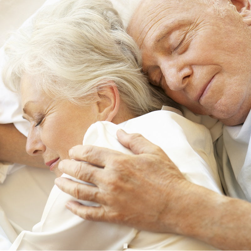 Older couple sleeping in bed happy