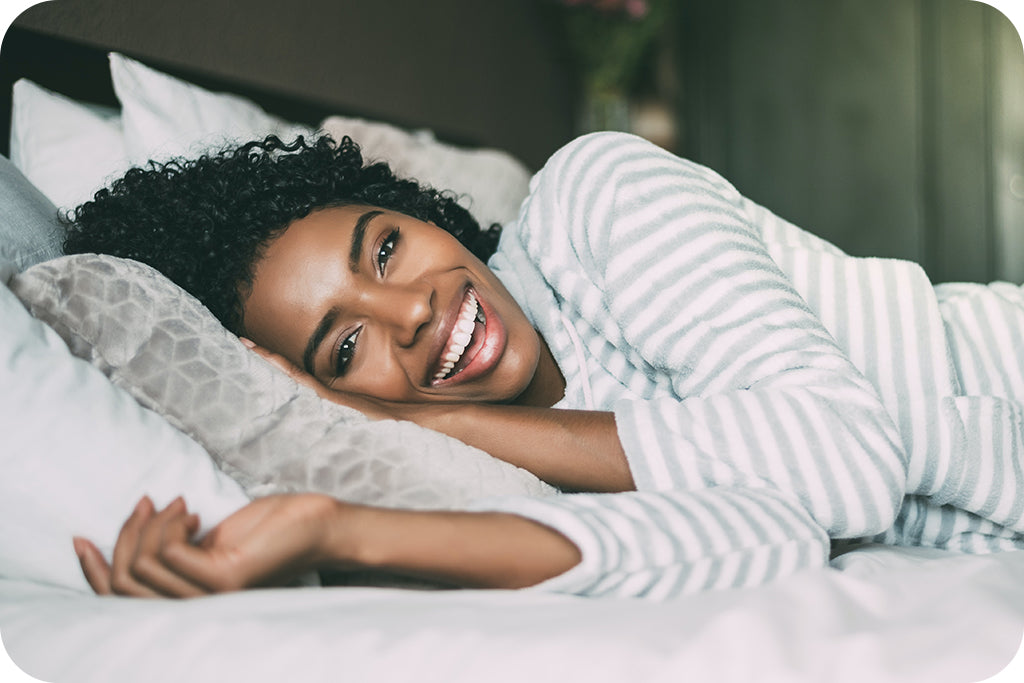 pretty black girl laying in bed with smile on her face