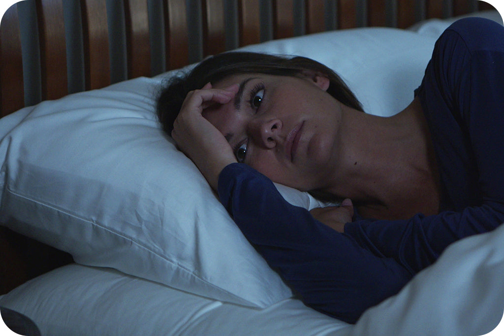 girl in blue pajamas laying in bed awake