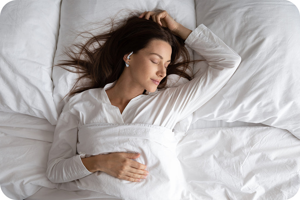 lady in white pajamas sleeping in bed with white comforter