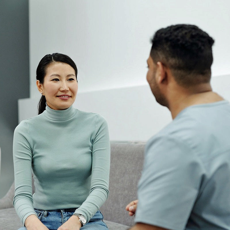 Man and woman talking while sitting on sofa